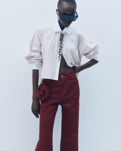 Person wearing a white striped shirt and red pants with a plain background