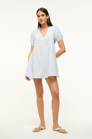 Woman wearing a blue gingham, V-neck mini dress with puff sleeves