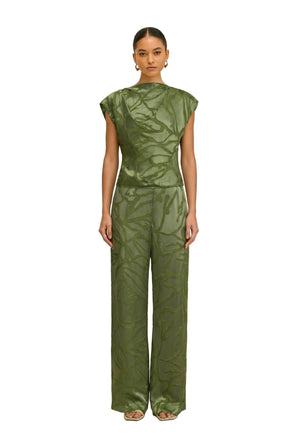 Woman wearing a green matching top and wide leg pant against a white background.