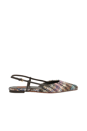 A single flat sandal with a multicolor woven pattern upper and dark brown leather straps, shown in profile against a light gray background.