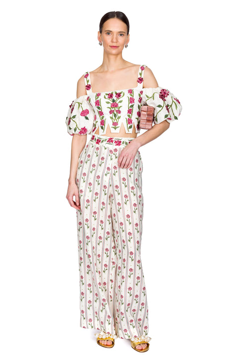 Woman wearing a floral off-shoulder top and long, matching pants on a white background from the front
