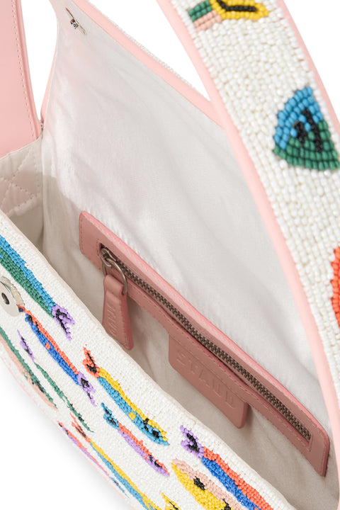 Inside of a white glass-beaded shoulder bag that depicts rainbow sardines, featuring light pink leather detailing and ivory lining. 