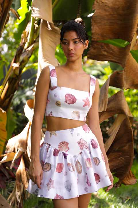 Model in the jungle in the matching sea shell printed top and skirt.