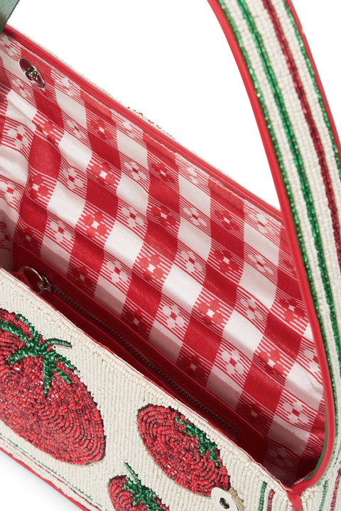 Detail shot of the inside of a glass beaded shoulder bag that features pictures of tomatoes and a red gingham lining. 