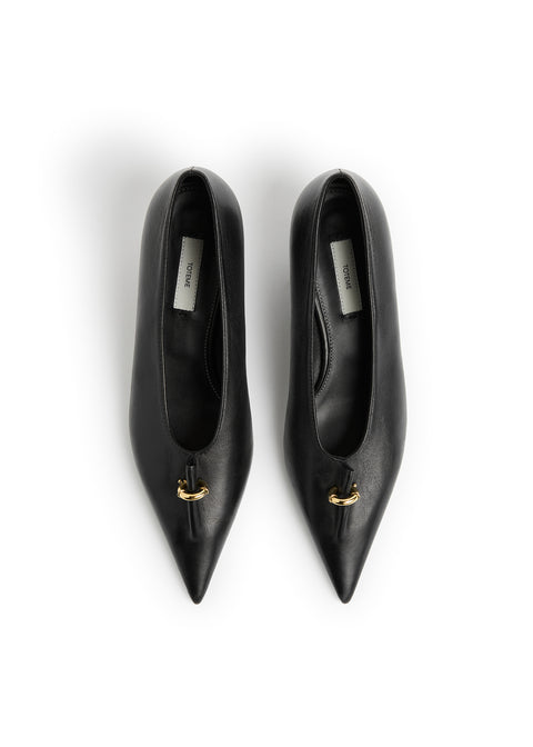 A pair of black leather pointed-toe pumps with a small gold detail on the vamp, photographed from directly above on a white background.