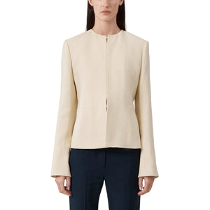 Woman wearing a beige blazer and dark pants on a light background