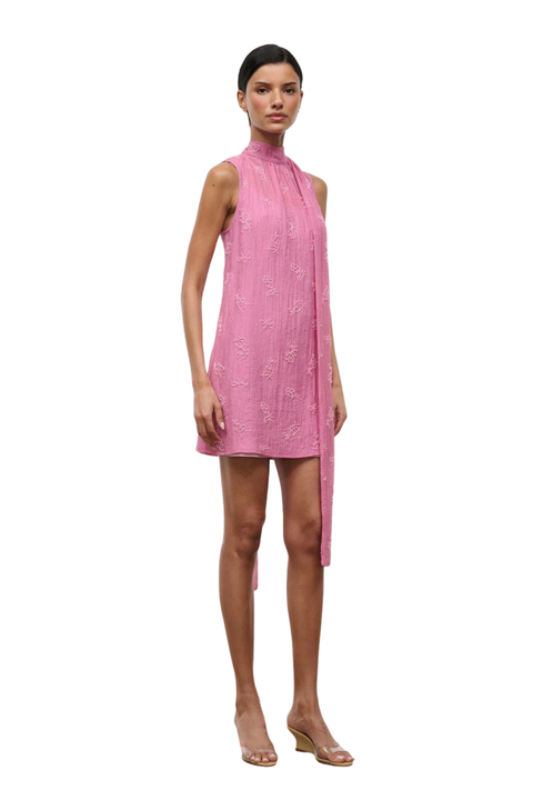 A woman wearing a pink high neck mini dress with beaded embellishments side angle