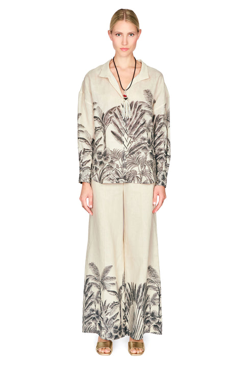 Woman wearing a patterned button down blouse and long pants on a white background