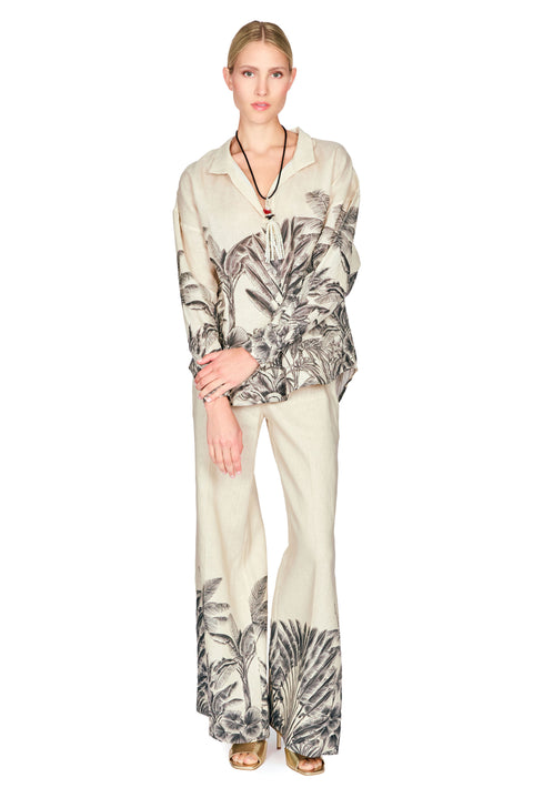 Woman wearing a patterned button down blouse and long pants on a white background
