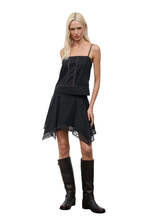 A woman wearing a black sleeveless top with a matching skirt
