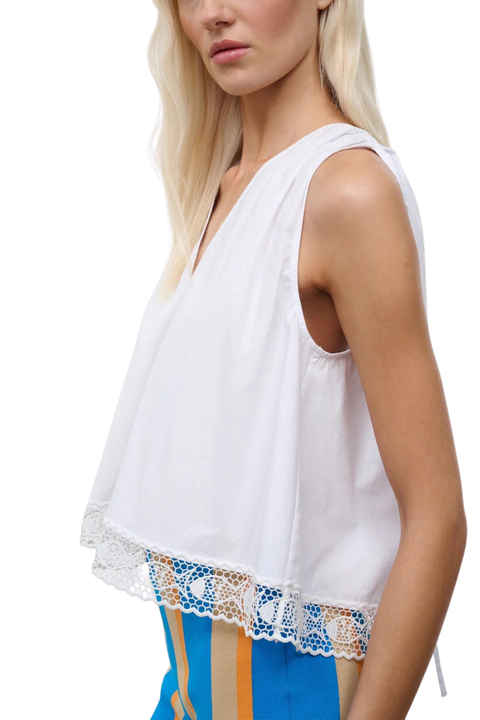 Close-up of a woman wearing a white sleeveless v-neck top with adjustable shoulder ties and fish embroidery