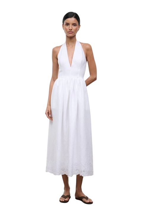 Woman wearing a long white halter neck dress on a white background