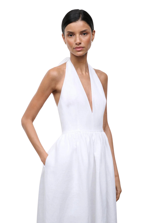 Woman wearing a long white halter neck dress on a white background close-up angle