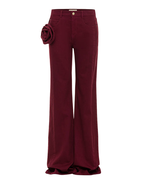 Maroon denim pants with a floral rosette detail on a white background