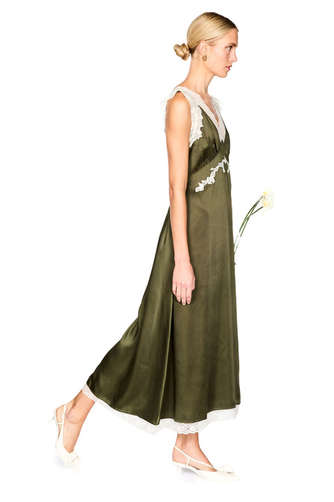A woman modeling a sleeveless olive green satin maxi dress with white lace trim on a plain white background.
