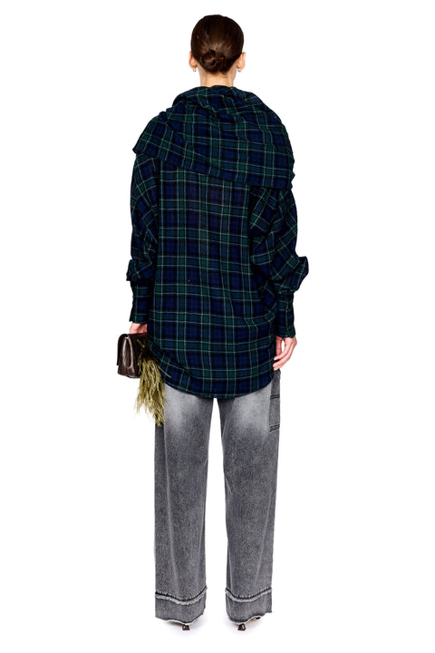A model shown from the back wearing a dark green and black plaid hooded shirt, gray wide-leg jeans, and holding a small brown handbag against a solid white background.