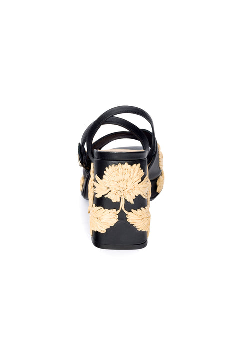 Back view of black platform sandal with woven leaf patterns on a white background.