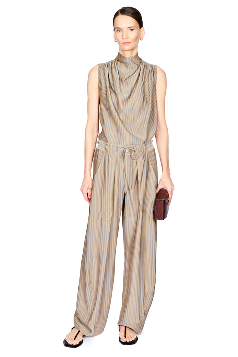 A model stands against a white background wearing a sleeveless, high-neck top and matching pants in a beige and brown vertical stripe pattern. The pant features a gathered waist with a matching fabric tie belt and wide-leg trousers.