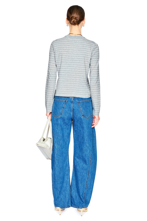 A model shown from the back wearing a gray and white striped long-sleeve top, wide-leg blue denim jeans, and holding a small white handbag against a solid white background.