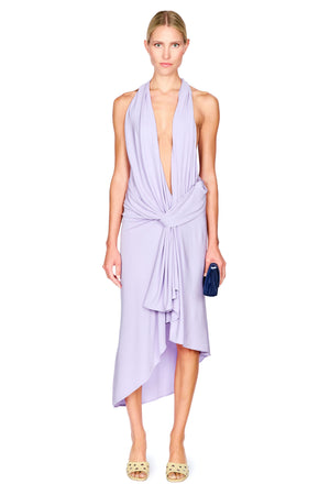 A woman wearing a purple halter midi dress with a low cut, draped neckline and waist