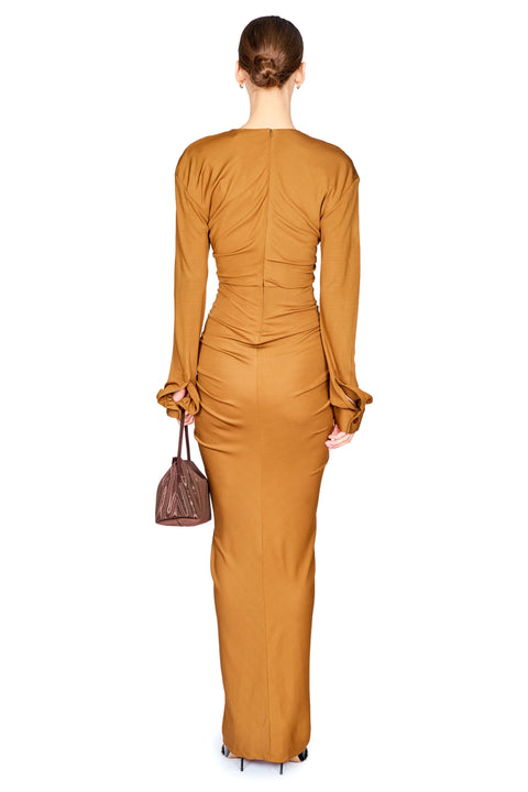 A woman shown from the back wearing a cognac brown long dress with long sleeves and a zipper down the back