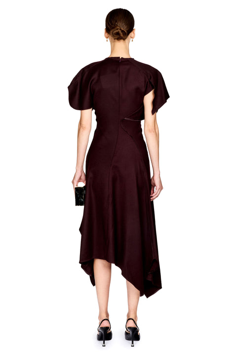 A woman viewed from the back wearing a dark burgundy midi dress with short puff sleeves, a high neck, and an asymmetrical draped hem. She is holding a small black clutch and wearing black heels against a plain white background.
