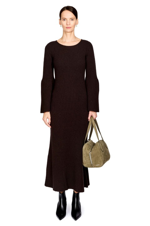 A model stands against a white background wearing a dark brown ribbed knit midi dress with long sleeves and holding an olive green suede shoulder bag.