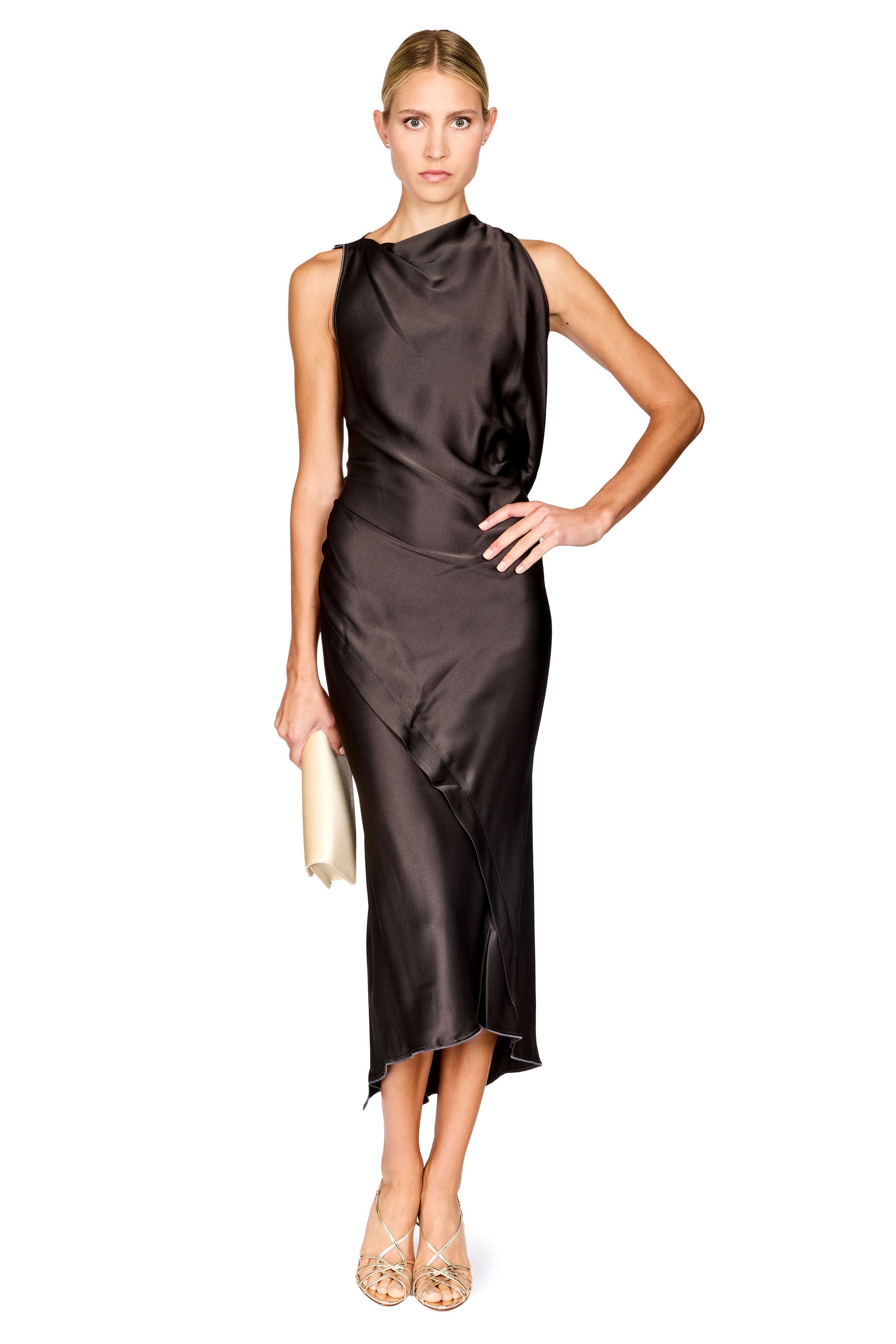 A woman modeling a sleeveless, high-neck, dark brown satin midi dress with a draped, gathered silhouette. She is holding a small cream clutch and wearing beige strappy heels, set against a plain white background.