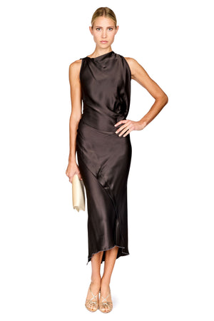 A woman modeling a sleeveless, high-neck, dark brown satin midi dress with a draped, gathered silhouette. She is holding a small cream clutch and wearing beige strappy heels, set against a plain white background.