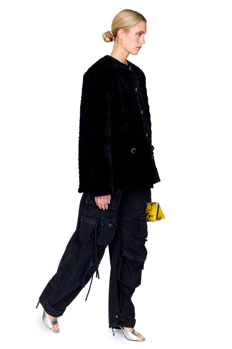 Side stance of quilted velvet evening jacket with gold buttons and cargo pants