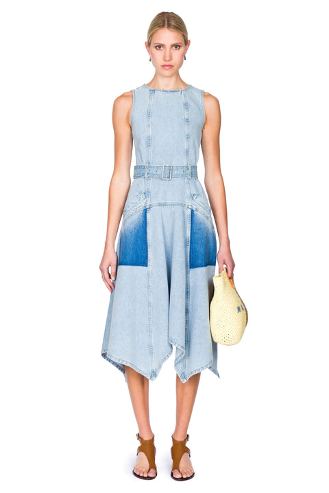 Woman wearing a blue denim dress holding a yellow handbag on a white background