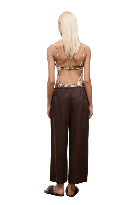 Woman wearing brown drawstring wide-leg pants on a white background back angle