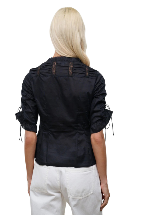 The back angle of a woman wearing a black button-up top with cinched sleeves and lace detailing