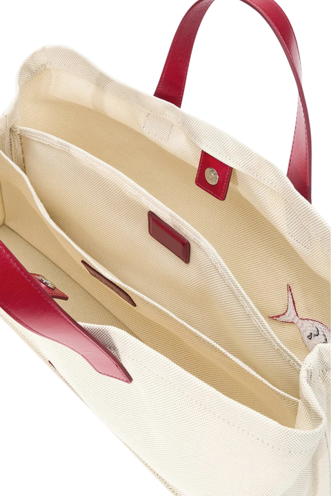 Close-up of a beige handbag with red handles and trim on a white background