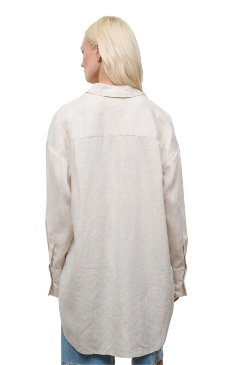 The back angle of a woman wearing a beige oversized linen button down