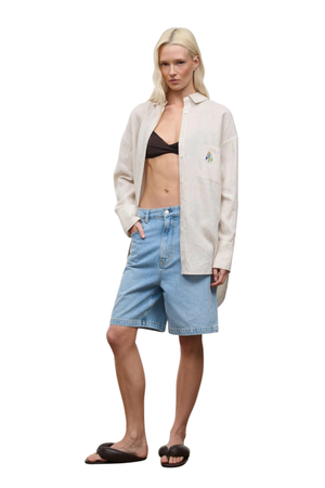 A woman wearing a beige oversized linen button down beach coverup shirt