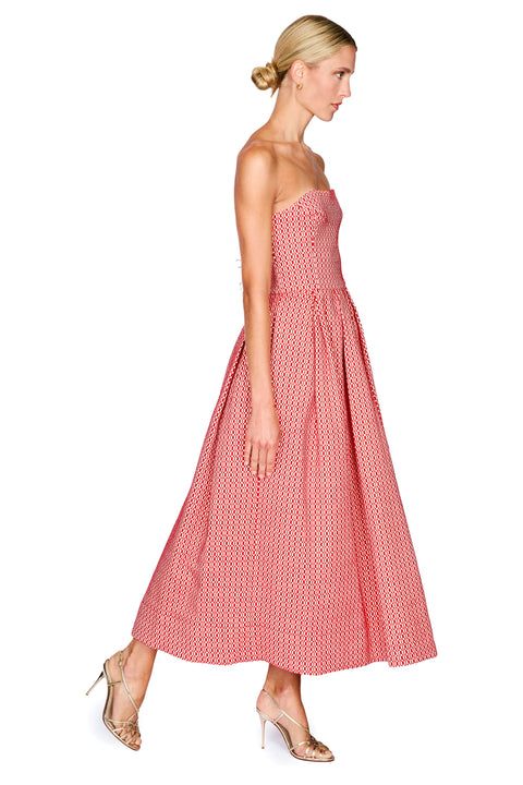 A woman modeling a strapless midi dress with a pink and white geometric pattern, shown from a side profile against a plain white background.