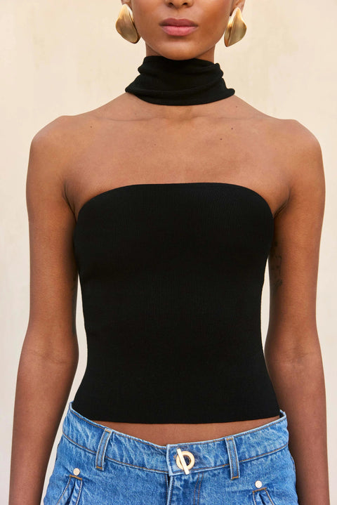 Woman wearing a strapless black top with an attached choker. 