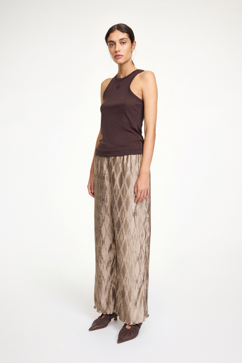 Woman wearing light brown textured pants with a dark brown tank top. 