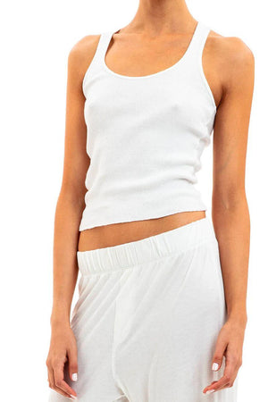 Model facing camera wearing ivory tank top